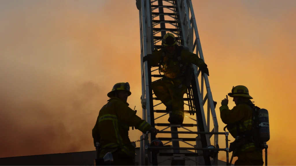 LA county firefighters climb a firetruck ladder